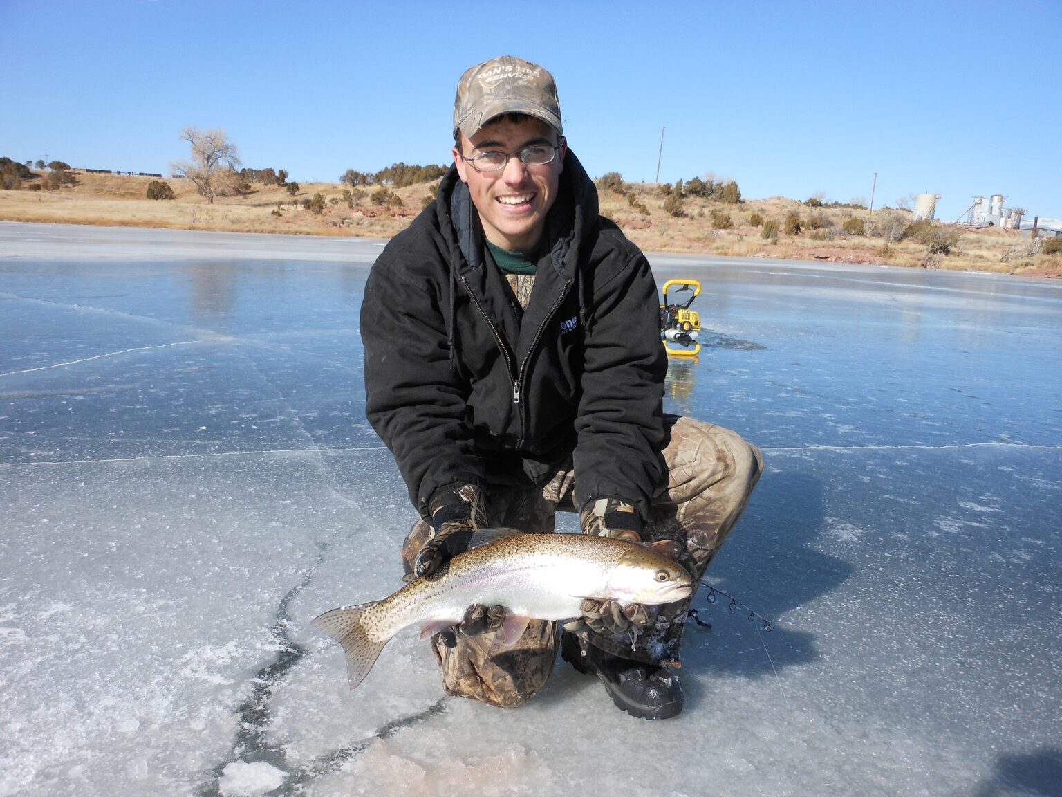 Angler with a trout on the ice in winter